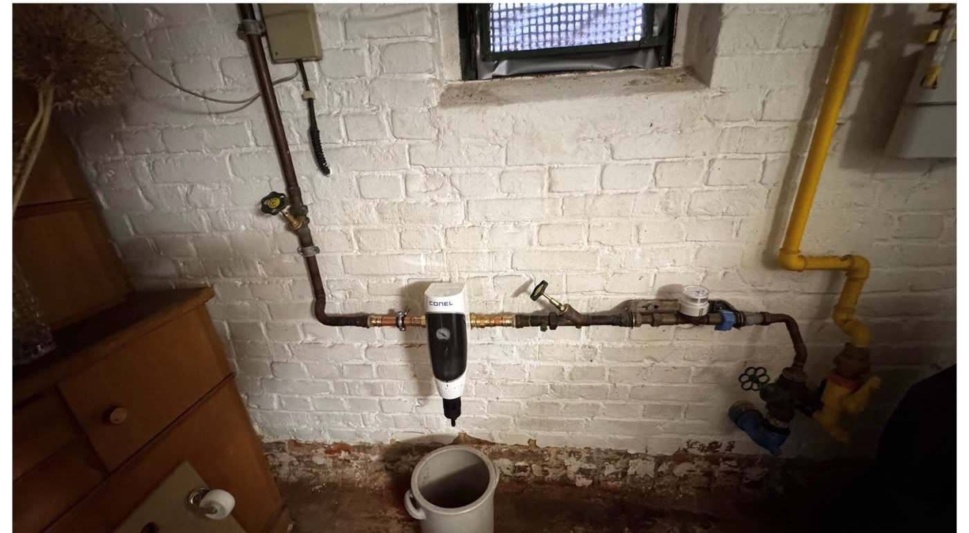 Nachher: erneuerte Kupferleitung mit neuem Druckminderer und Wasserzähler an derselben Kellerwand.