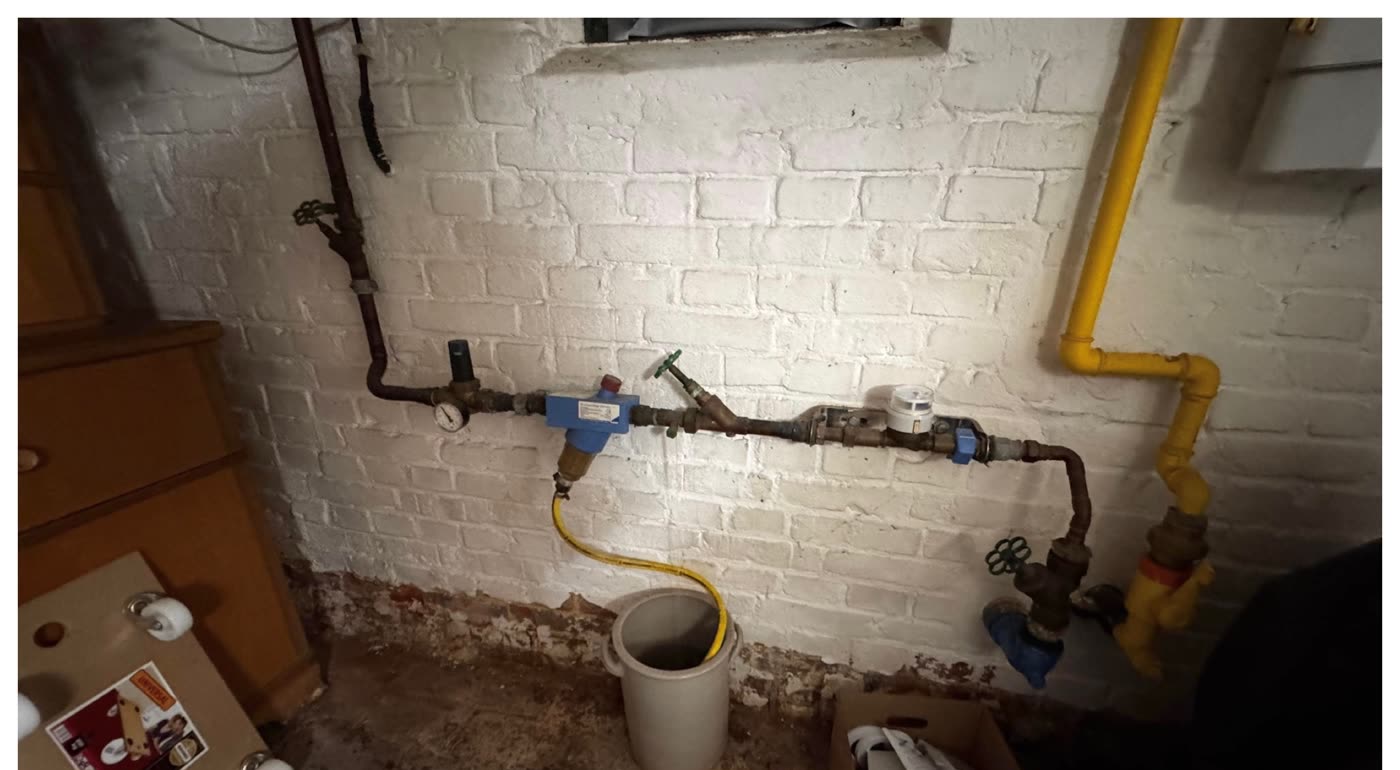 Vorher: alte Kupferleitung mit Druckminderer und Wasserzähler an einer Kellerwand.